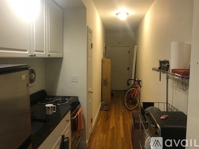 A kitchen with a stove top oven and a bicycle in the hallway.