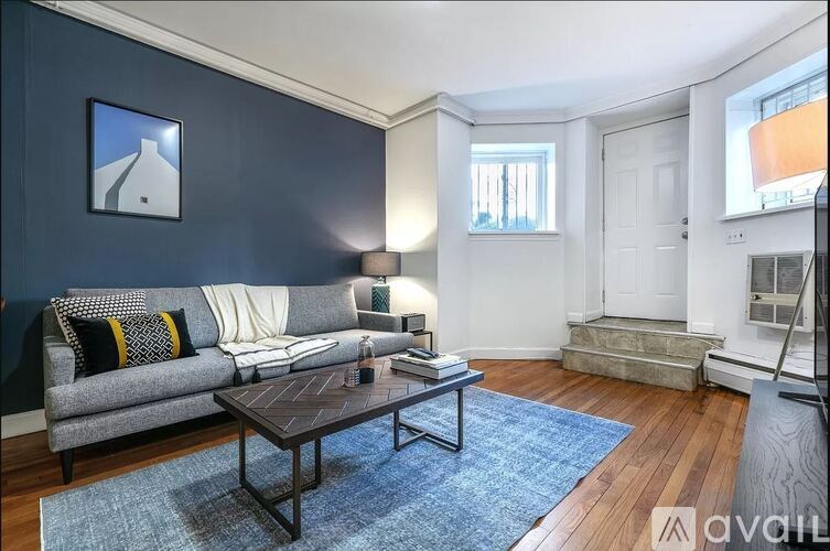 A living room with a grey couch, a coffee table, and a blue rug.