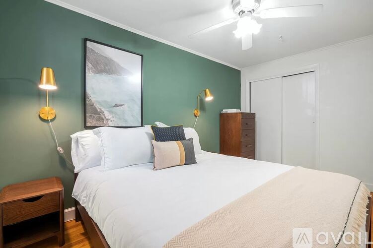 A bedroom with a bed, two lamps, and a painting on the wall.