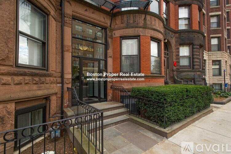 A brown building with a balcony and a sign that says Boston Proper Real Estate.