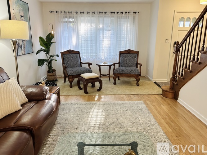 A brown leather couch with a glass table in front of it.
