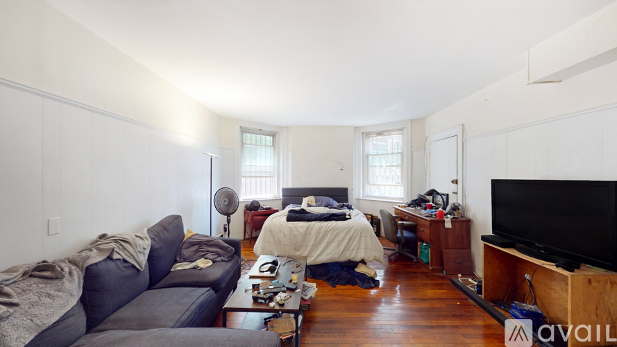 A living room with a couch, a bed, and a television.
