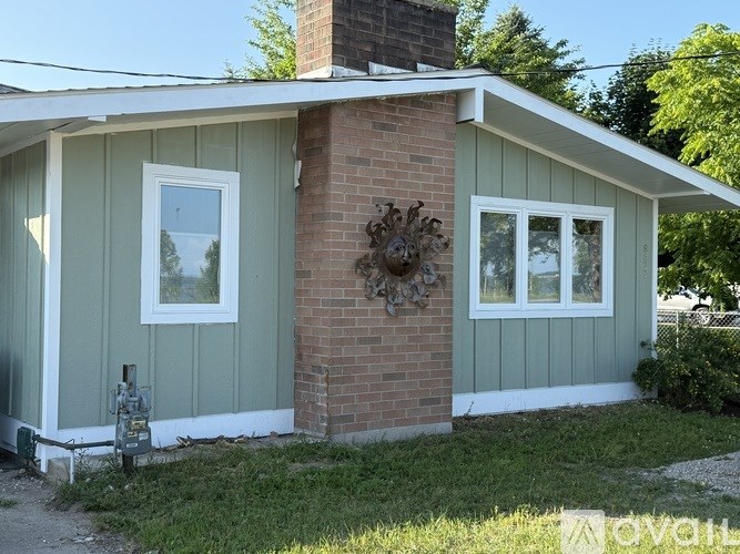 A house with a green siding and a brick chimney.