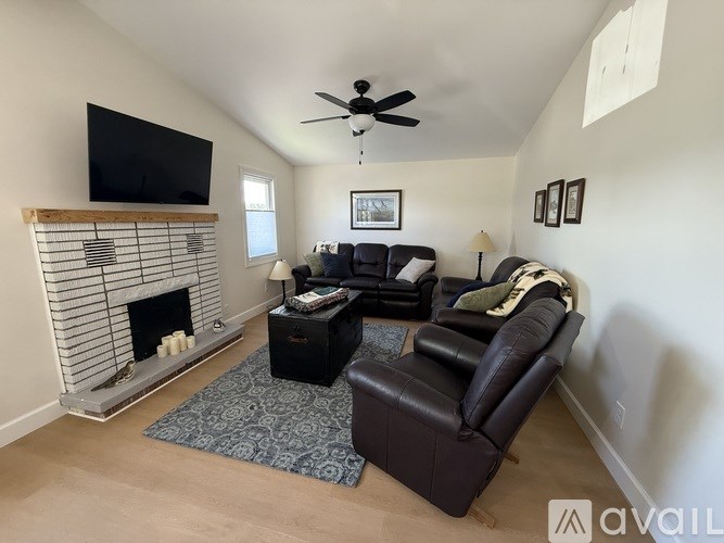 A living room with a fireplace, a couch, a chair, and a television.