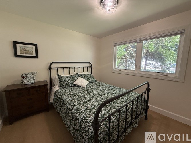 A bedroom with a bed, nightstand, and window.