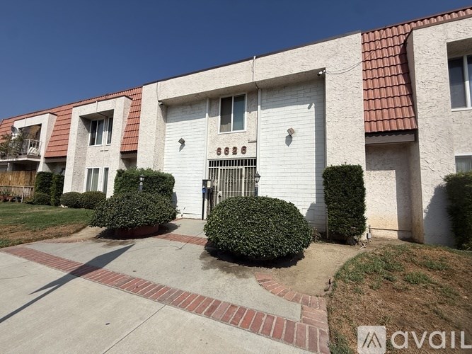 A white house with a red roof and a black gate in front.