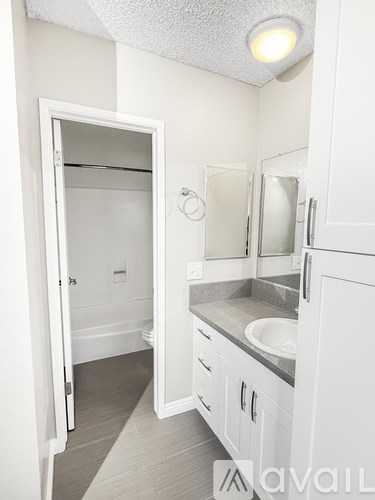 A bathroom with a sink, mirror, and a door.