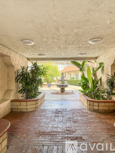 A patio with a brick floor and a fountain in the middle.