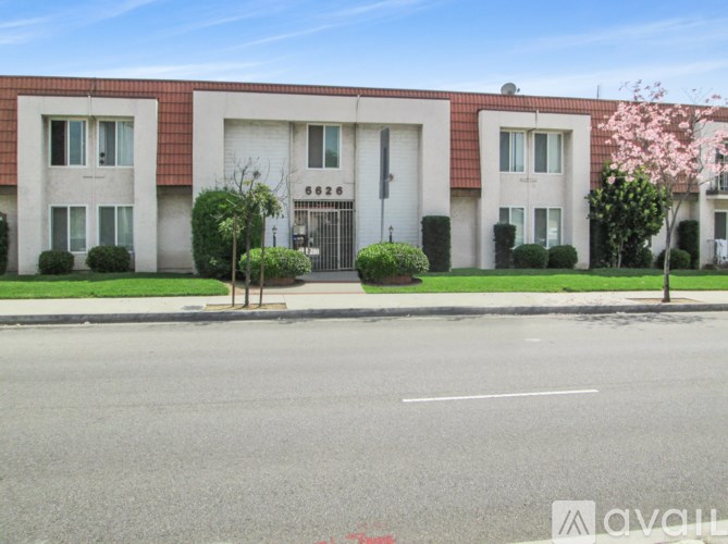 A building with a red roof and white walls with windows and a gate in the middle.