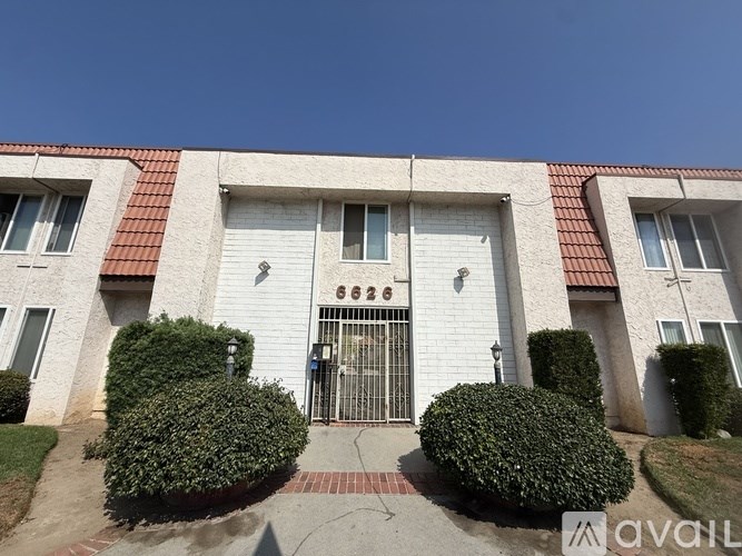 A white building with a red roof and a black gate in the center.