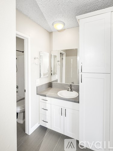 A bathroom with a sink, mirror, and cabinets.