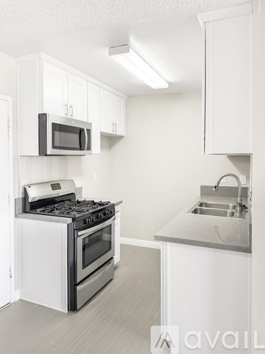 A kitchen with white cabinets and a stove top oven.