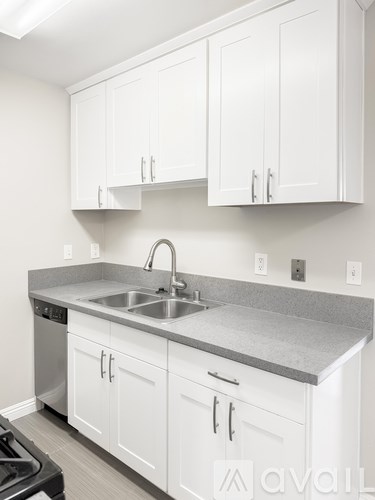 A kitchen with white cabinets and a grey countertop.