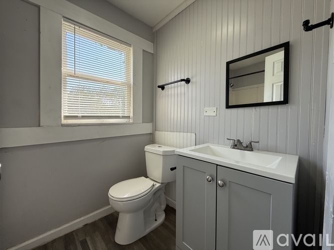 A bathroom with a toilet, sink, and a window.