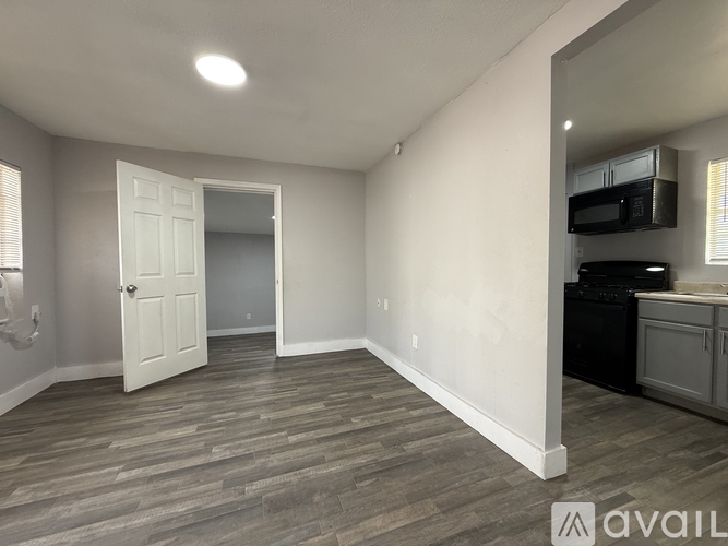 A room with a white door and a microwave on the counter.