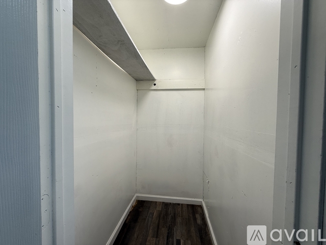 A small, empty room with a wooden floor and white walls.