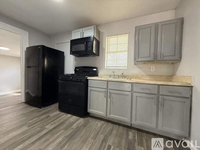 A kitchen with black appliances and grey cabinets.