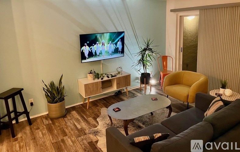 A living room with a television, a sofa, a coffee table, and a plant.