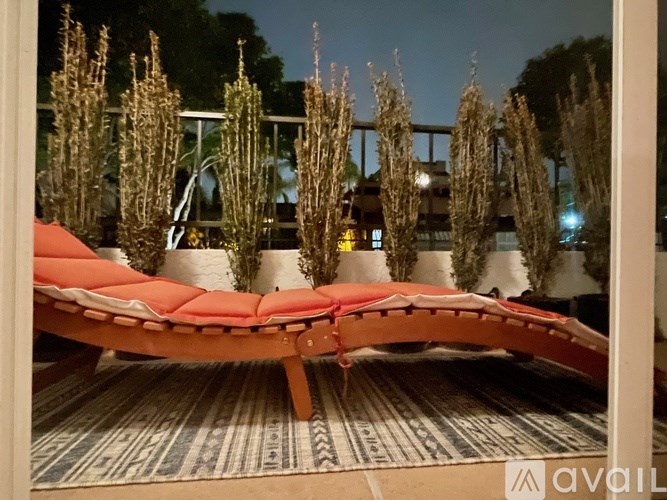 A red couch is in front of a mirror reflecting trees.