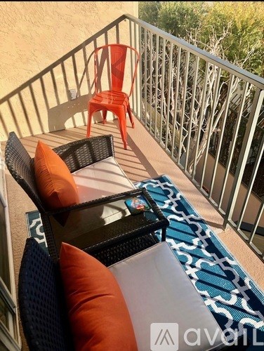 A balcony with a table, chairs and a blue and white rug.