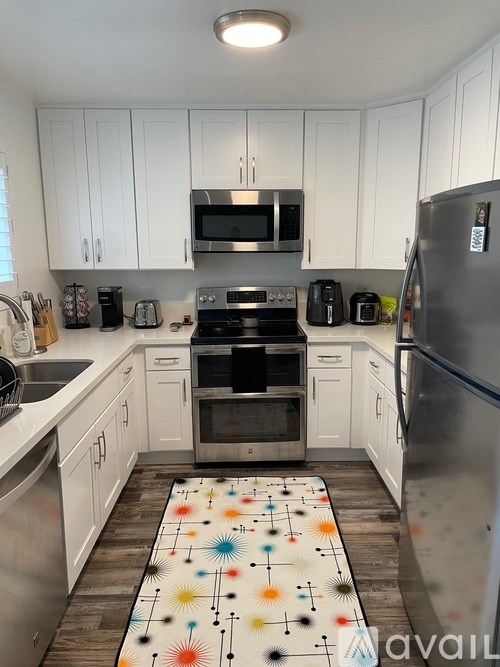 A kitchen with white cabinets and a patterned rug on the floor.