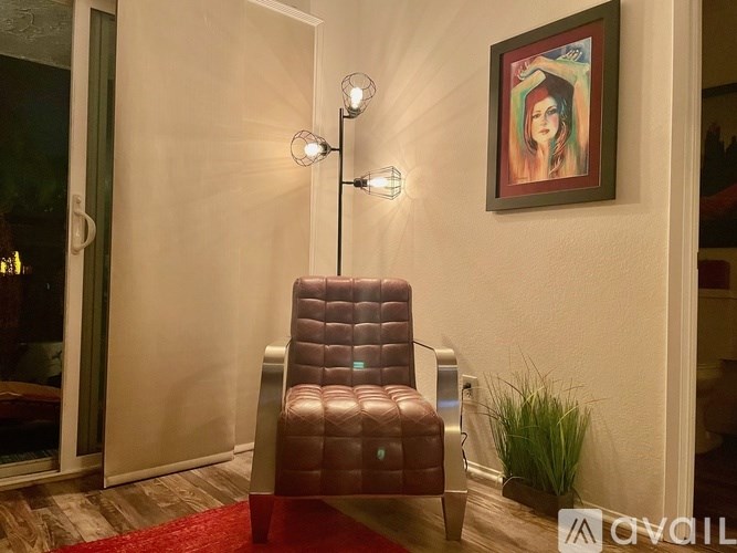 A brown leather chair is in front of a wall with a framed picture of a woman.