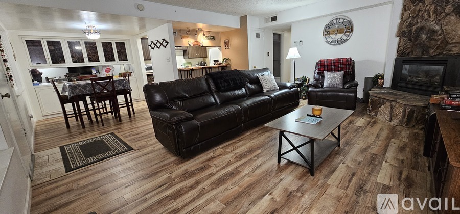 A living room with a black leather couch and a wooden coffee table.