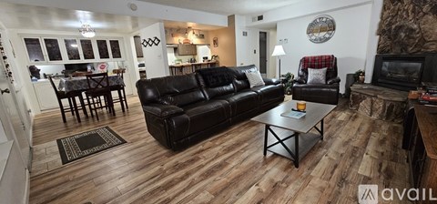 A living room with a black leather couch and a wooden coffee table.