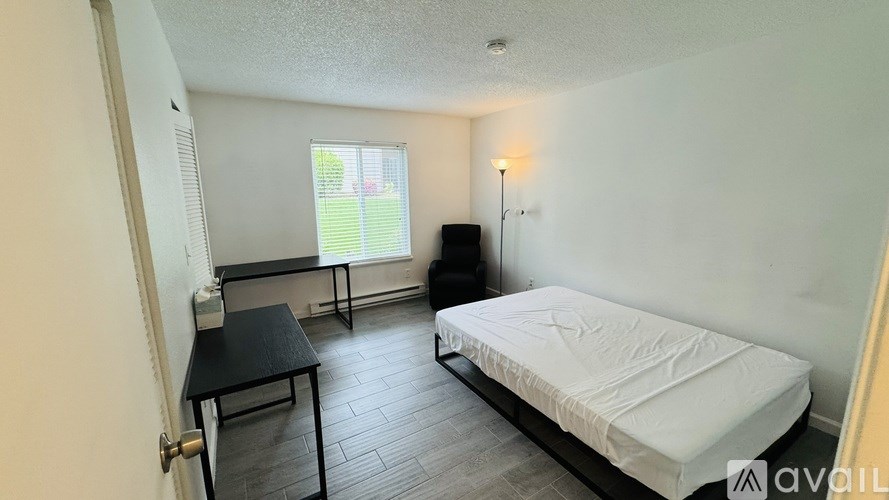 A bedroom with a bed, a table, and a window.
