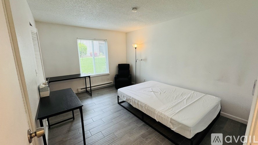 A bedroom with a bed, chair, and desk.