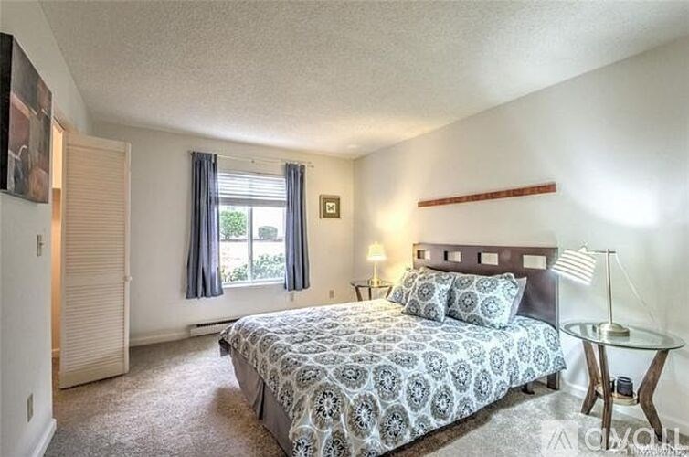 A bedroom with a patterned bedspread and a bed with a wooden headboard.