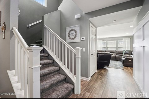 A staircase with white railings leads to a living room with a couch and a coffee table.