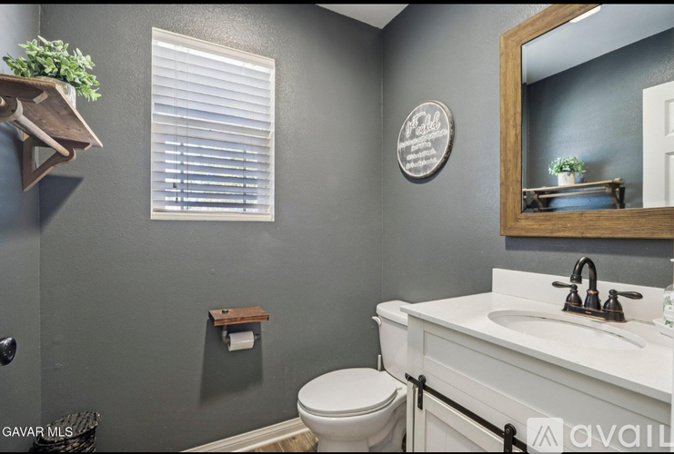 A bathroom with a toilet, sink, and mirror.