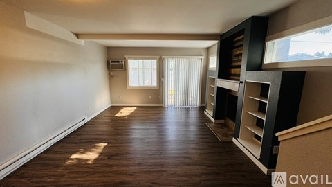 A spacious room with wooden floors and a window with blinds.