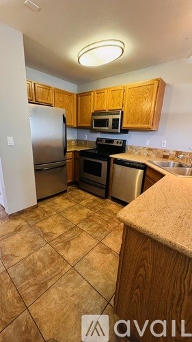 A kitchen with a refrigerator, microwave, oven, and sink.