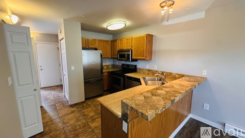 A kitchen with a granite counter top and wooden cabinets.
