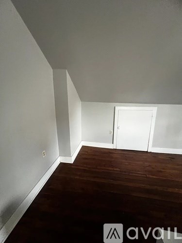 A room with a white door and wooden floor.