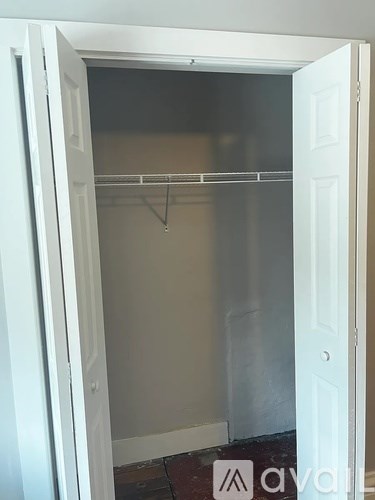 A white door is open to a room with a clothes hanger.