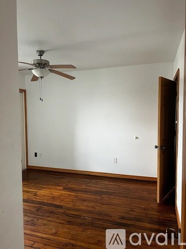 A room with a ceiling fan and wooden floors.