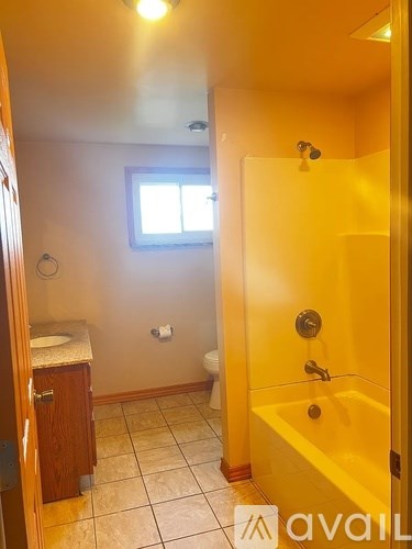A bathroom with a yellow door and a window.