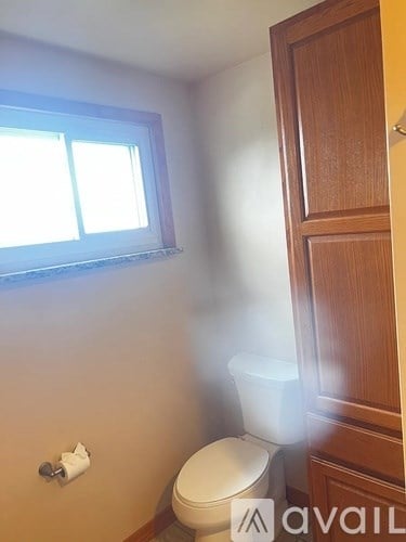 A small bathroom with a toilet and a window.