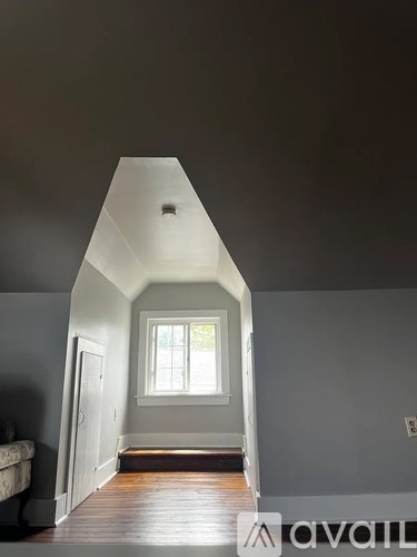 A room with a window and a wooden floor.