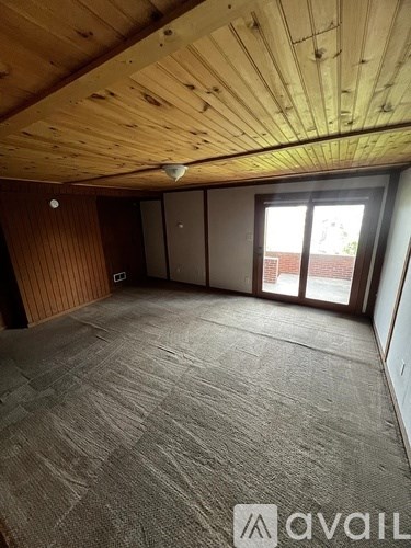 A room with wooden ceiling and carpeted floor.