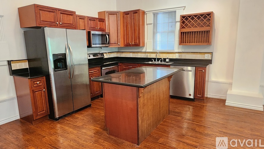 A kitchen with wooden cabinets and a black refrigerator.