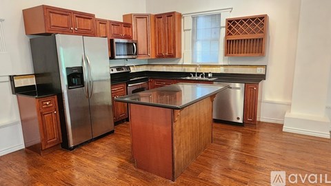 A kitchen with wooden cabinets and a black refrigerator.