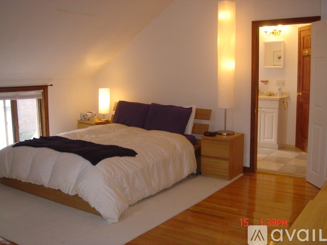 A bedroom with a large bed and a wooden nightstand.