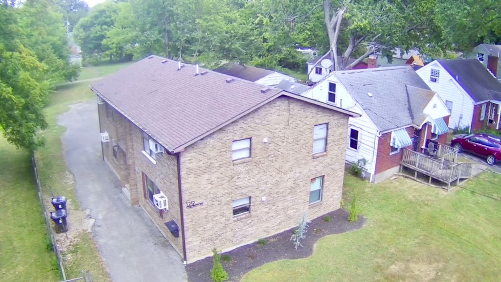 A house with a brown roof is surrounded by greenery.