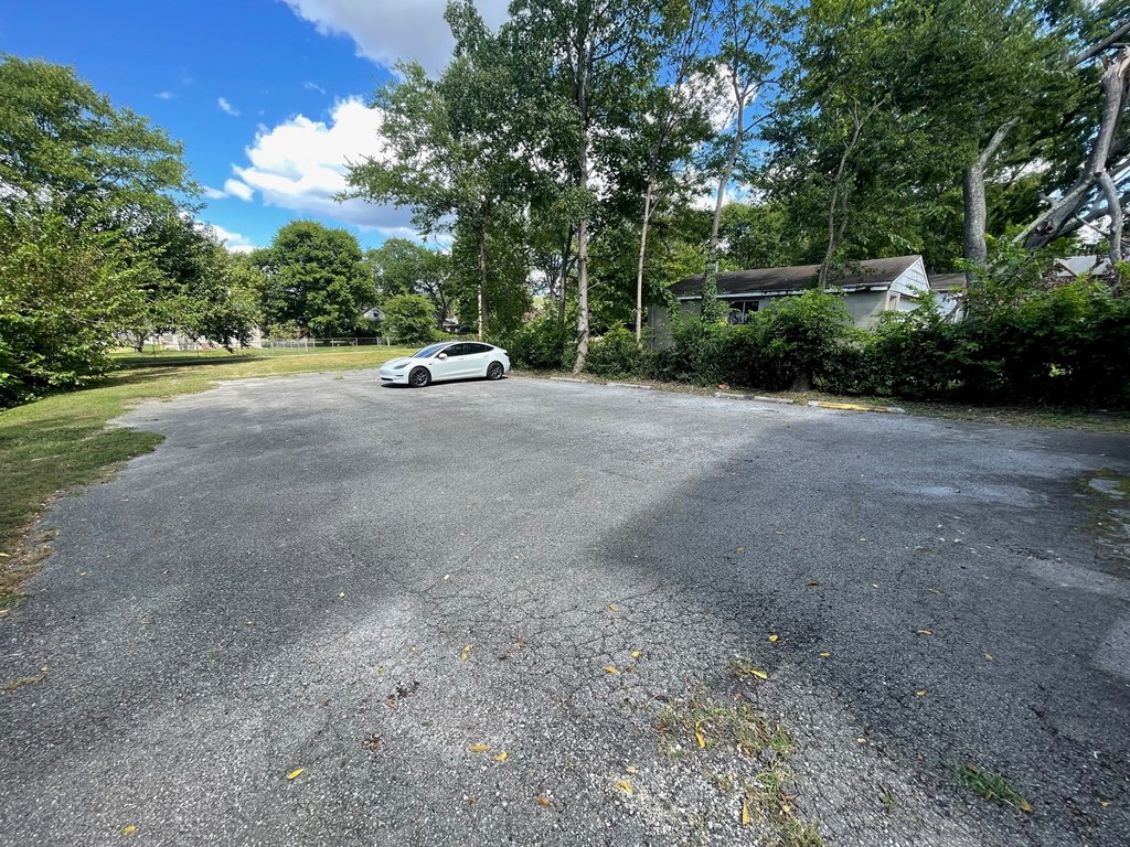 A car is parked in a driveway surrounded by trees.