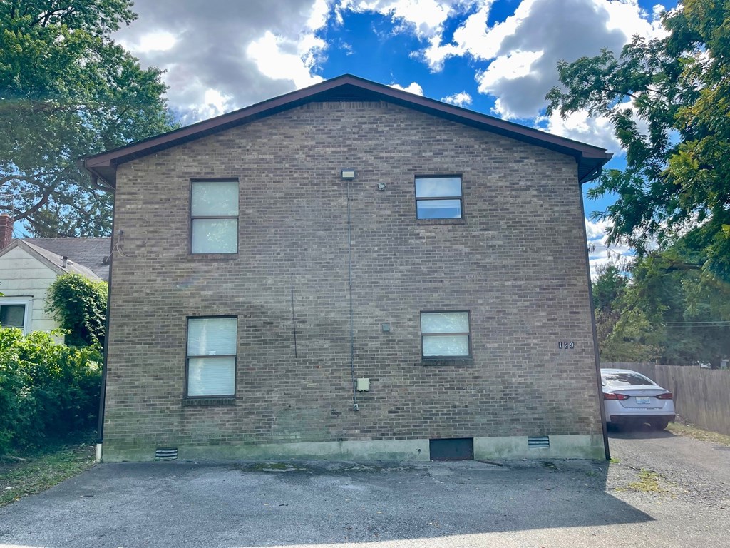 A two-story brick house with a car parked in front.