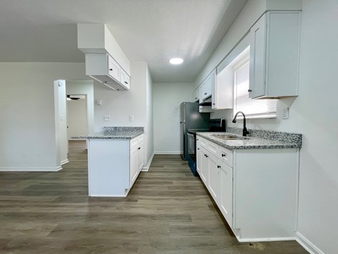 A kitchen with white cabinets and a granite countertop.